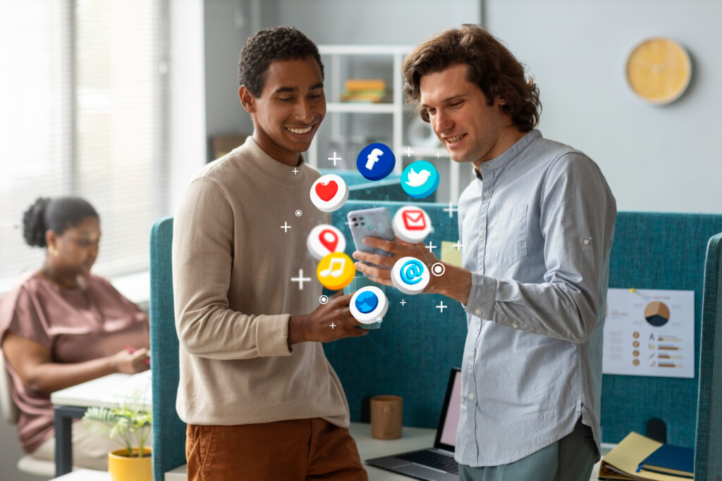 Two men focused on a screen displaying social icons, possibly engaged in online networking or social media activities.